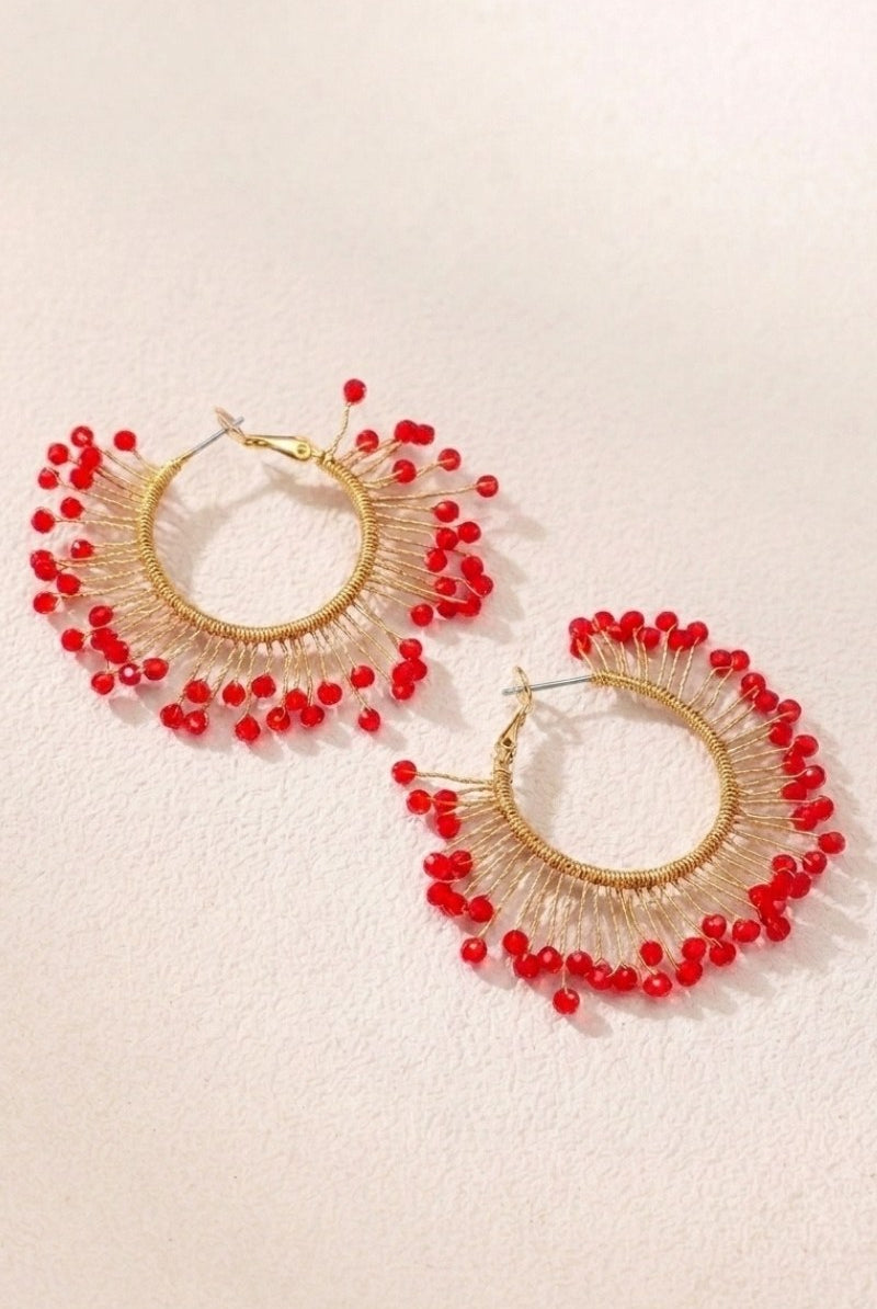 Solburst wire-wrapped beaded sunburst hoop earrings in the Crimson variant on a warm beige background