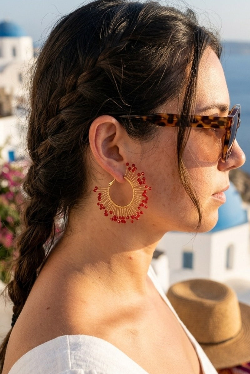Model wearing solburst wire-wrapped beaded sunburst hoop earrings in the Crimson variant, view 2