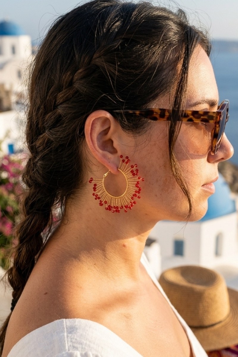 Model wearing solburst wire-wrapped beaded sunburst hoop earrings in the Crimson variant, view 2