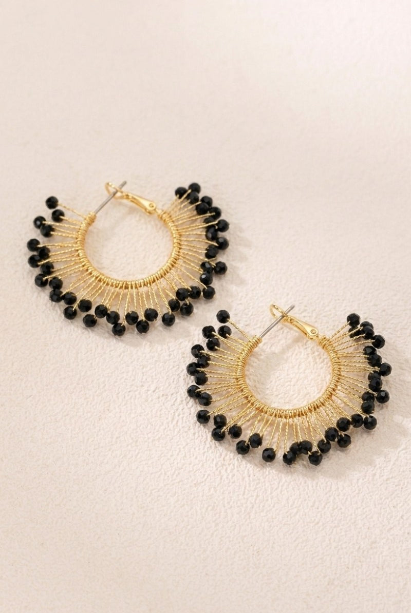 Solburst wire-wrapped beaded sunburst hoop earrings in the Noir variant on a warm beige background
