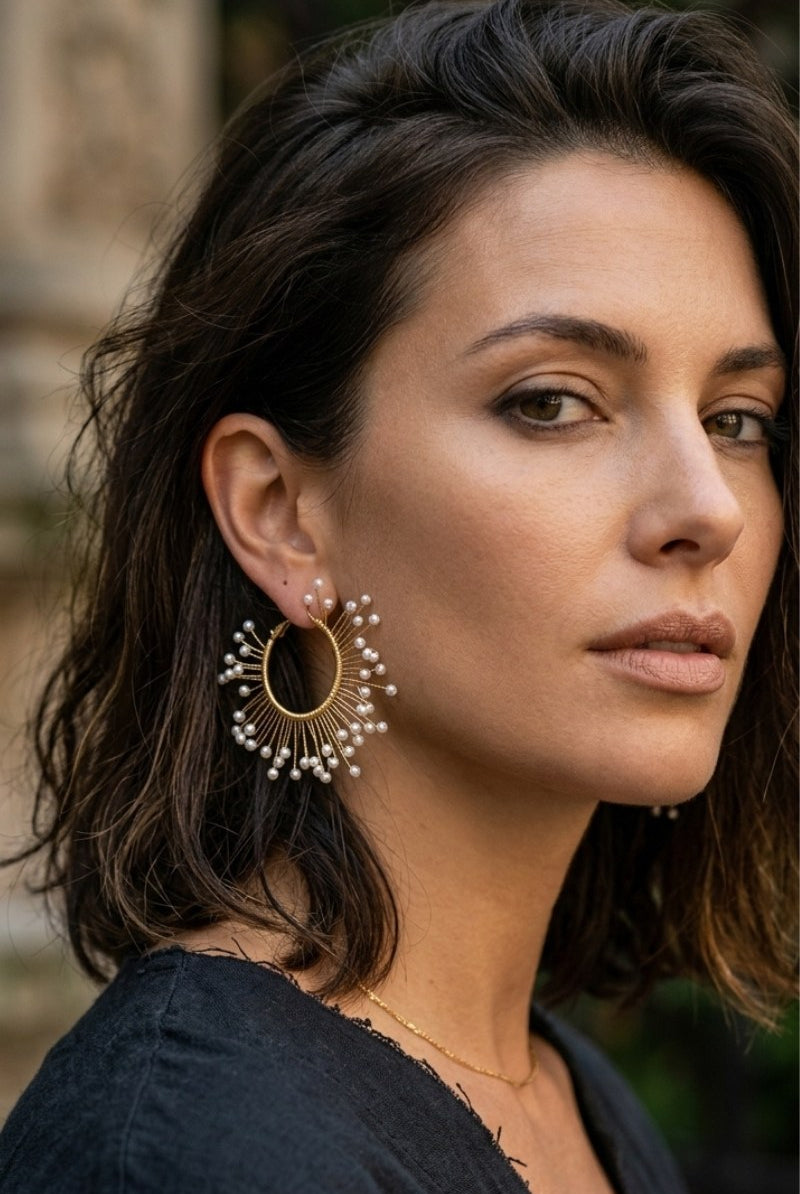 Model wearing solburst wire-wrapped beaded sunburst hoop earrings in the Pearl variant, view 2