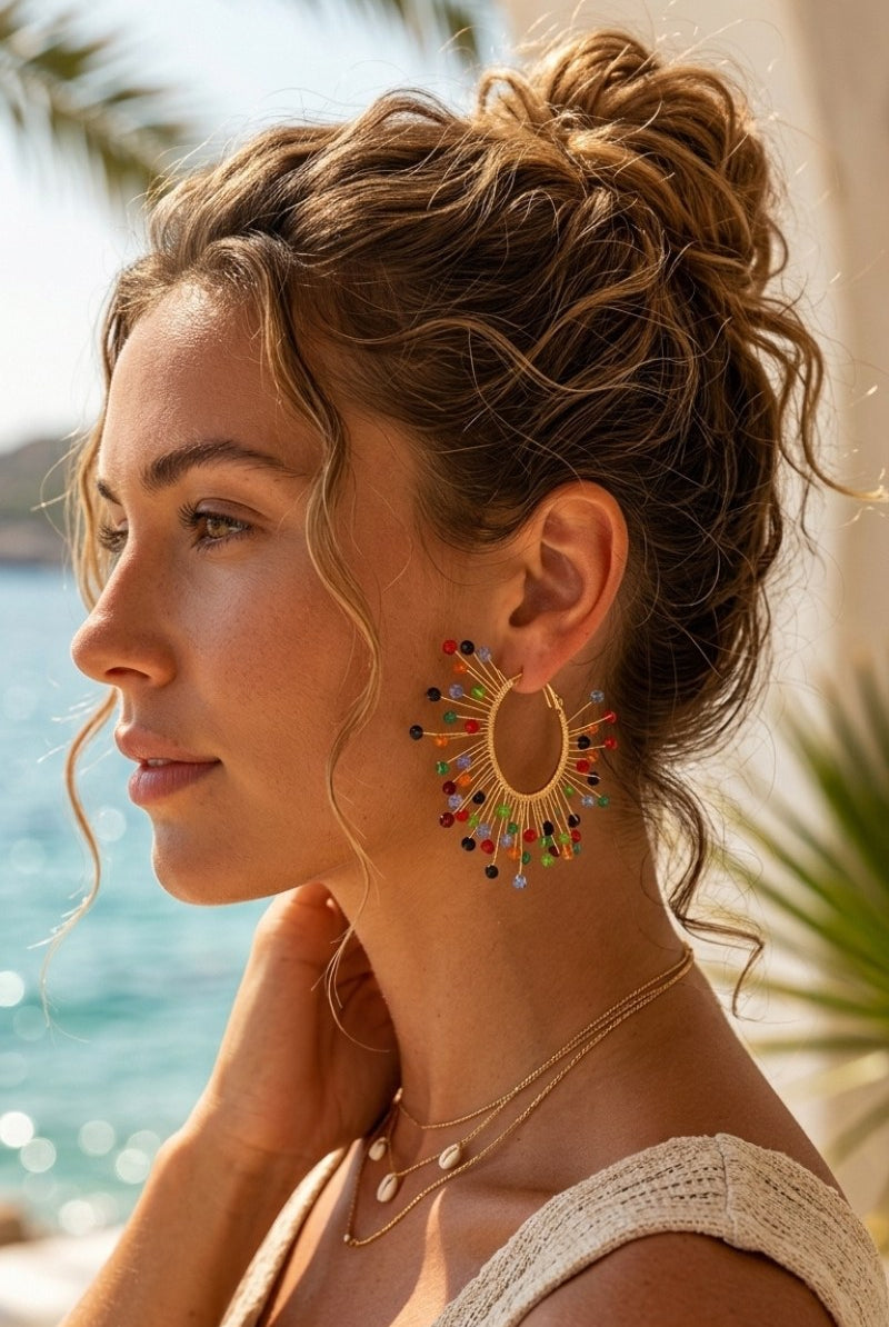 Model wearing solburst wire-wrapped beaded sunburst hoop earrings in the Prism variant, view 1
