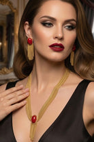 Stunning model wearing the Eclipse crimson red tassel necklace and matching gold fringe earrings, an ideal luxury jewelry set for high-end events in Monaco or red carpet appearances in Cannes.