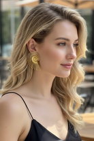 Detailed view of All-Glows gold Nautilus Spiral earrings following the Fibonacci sequence design. This sculptural jewelry piece creates a bold contrast against a minimalist black top, ideal for modernist fashion enthusiasts.