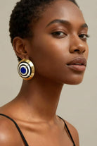 Large cobalt blue and white enamel concentric circle dôme earrings on a model, showing oversized fit and high-shine finish.