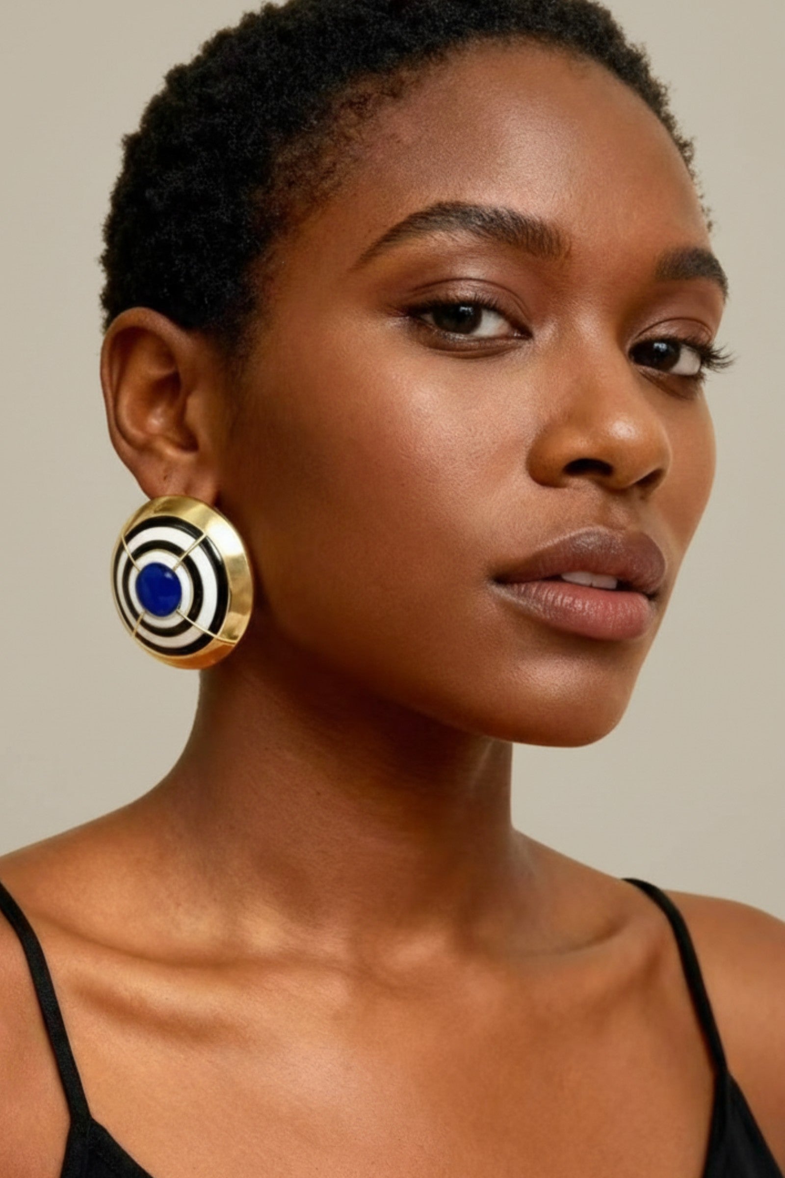 Woman wearing oversized ribbed gold dome earrings for a mob wife aesthetic look.