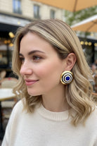 Model wearing All-Glows Grand Muse cobalt blue enamel dome studs with a cream knit sweater. These bold architectural earrings add a touch of casual luxury to everyday autumn and winter outfits.