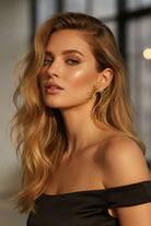 Glamorous model wearing 18K gold plated sunburst statement earrings during golden hour. Elegant modernist jewelry perfect for evening galas and formal events.