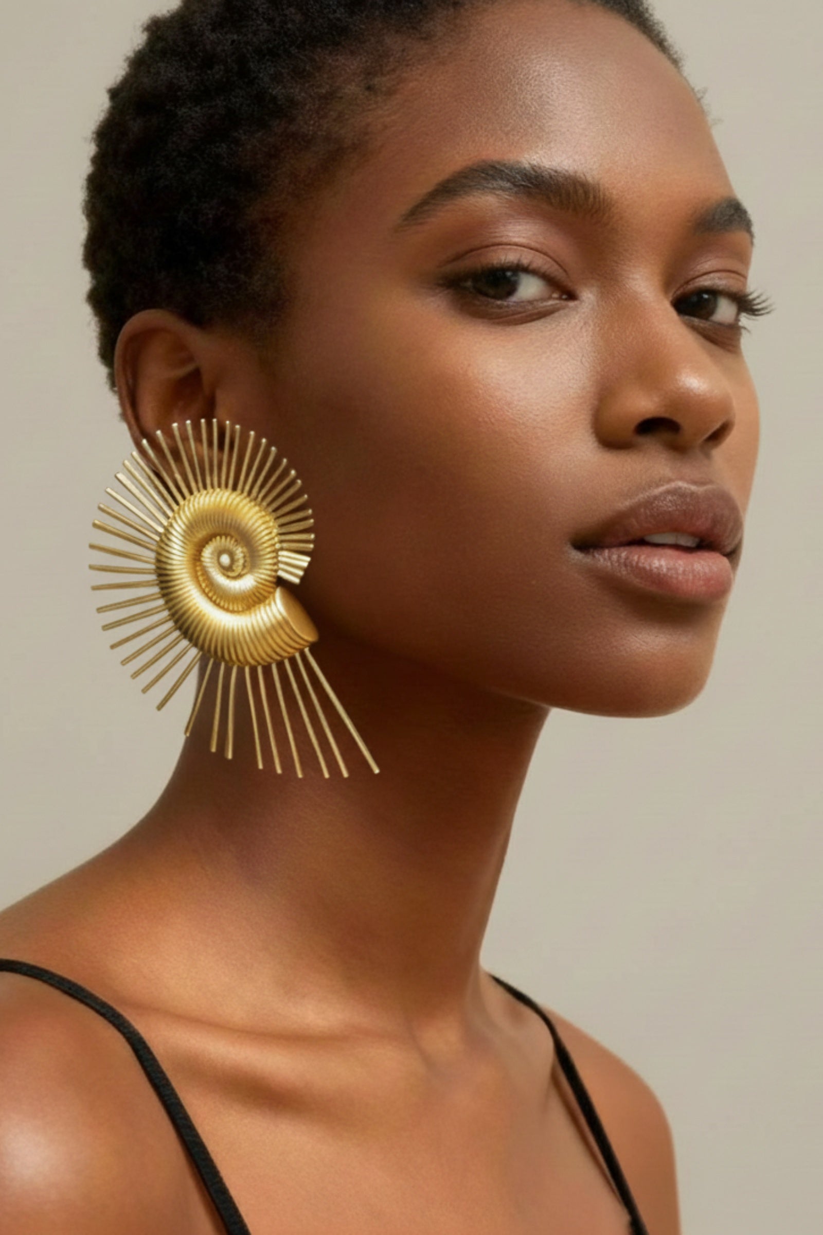 Large golden spiral wire earrings with a nautilus-inspired geometric design earrings on a model, showing oversized fit and high-shine finish.