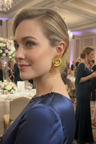 Close-up portrait of a model wearing All-Glows modernist gold spiral earrings. The architectural silhouette and balanced weight make these earrings a perfect luxury gift for women who appreciate artistic design.