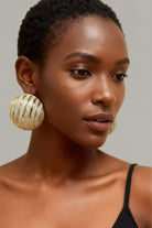 Large ribbed two-tone dôme earrings in gold and silver on a model, showing oversized fit and high-shine finish