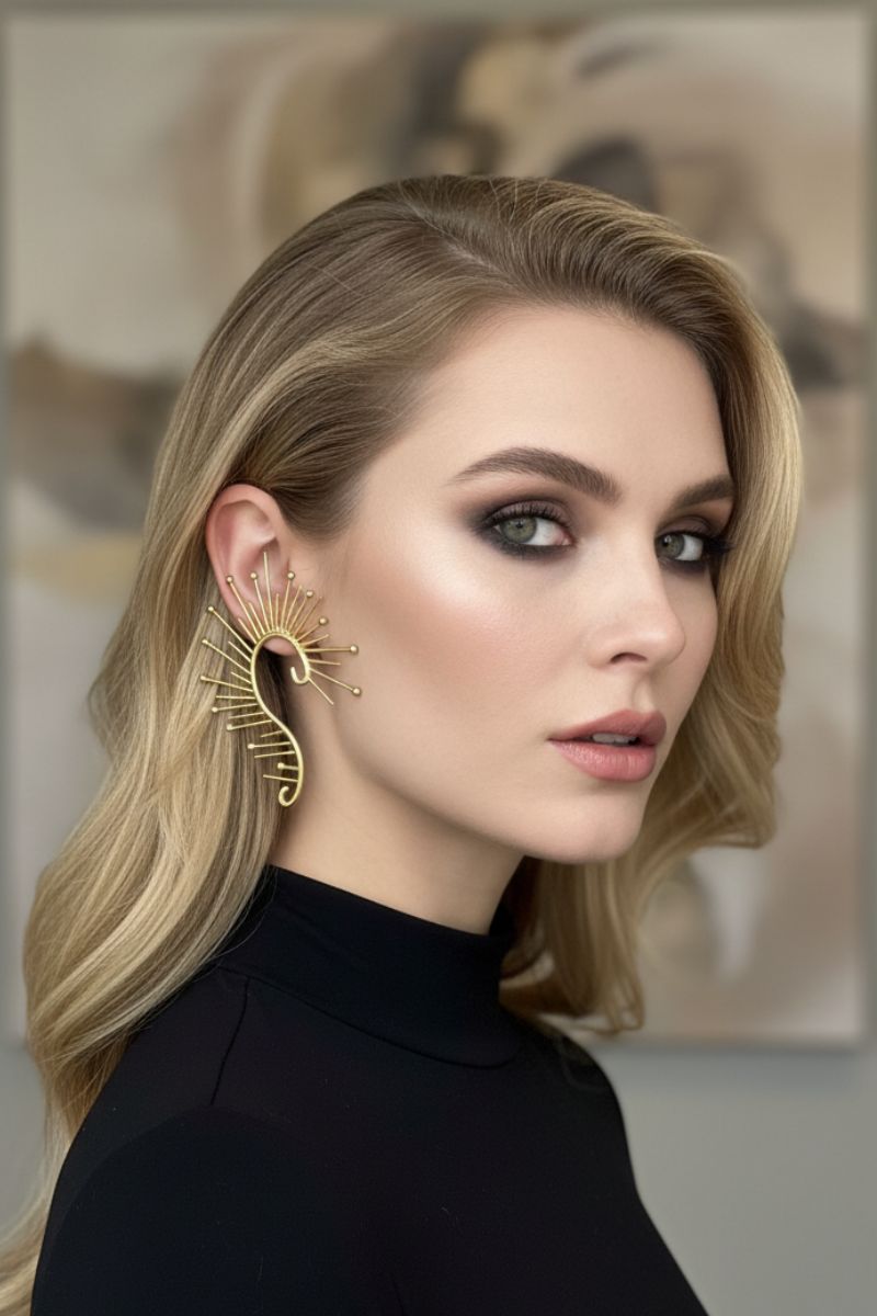 ide profile of a model with bold smoky eye makeup wearing All-Glows sculptural gold sunburst ear crawlers. Avant-garde statement jewelry for high-fashion editorial looks.