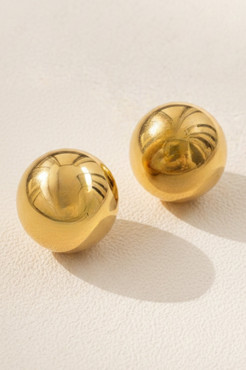 Close-up shot of the Aura Sculpted Dome Studs on a soft beige background, highlighting the smooth texture of these lightweight hollow gold ball studs, popular in US and European boutique indie designer jewelry trends.