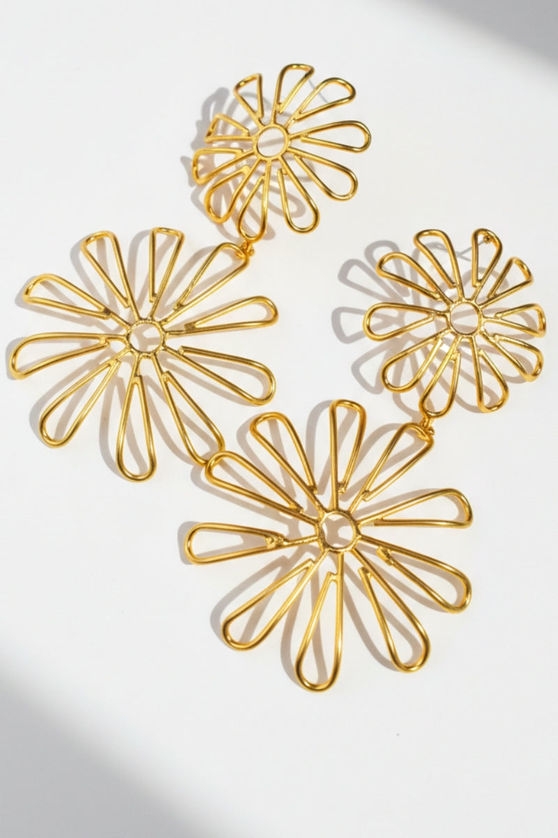 Close-up of layered daisy cutout earrings, showing the lightweight tiered structure and elegant floral silhouette.