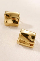 Crinkled gold square statement studs on a warm beige background