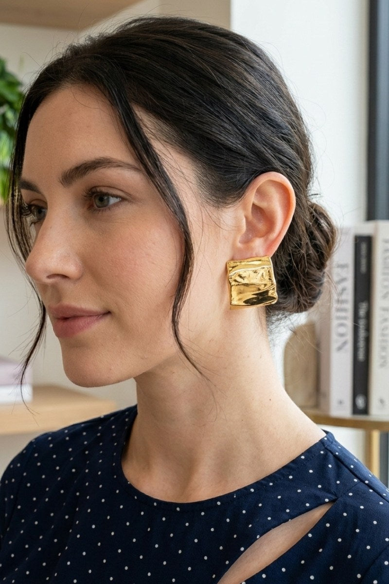 Model wearing crinkled gold square statement studs, view 2