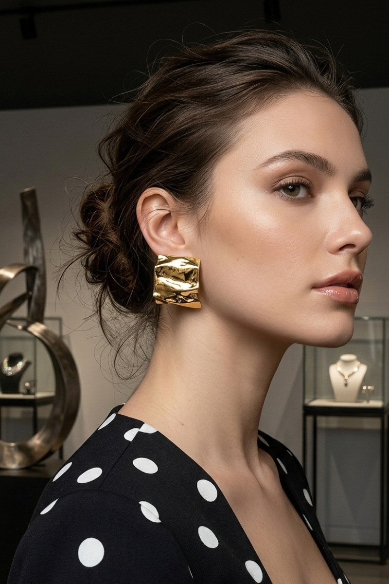 Model wearing crinkled gold square statement studs, view 3