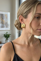 Model wearing crinkled gold square statement studs, view 5