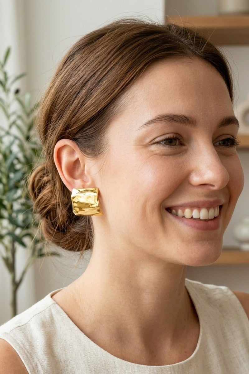 Model wearing crinkled gold square statement studs, view 6