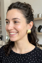 Model wearing crinkled gold square statement studs, view 1