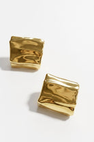 Pair of crinkled gold square statement studs on a white background