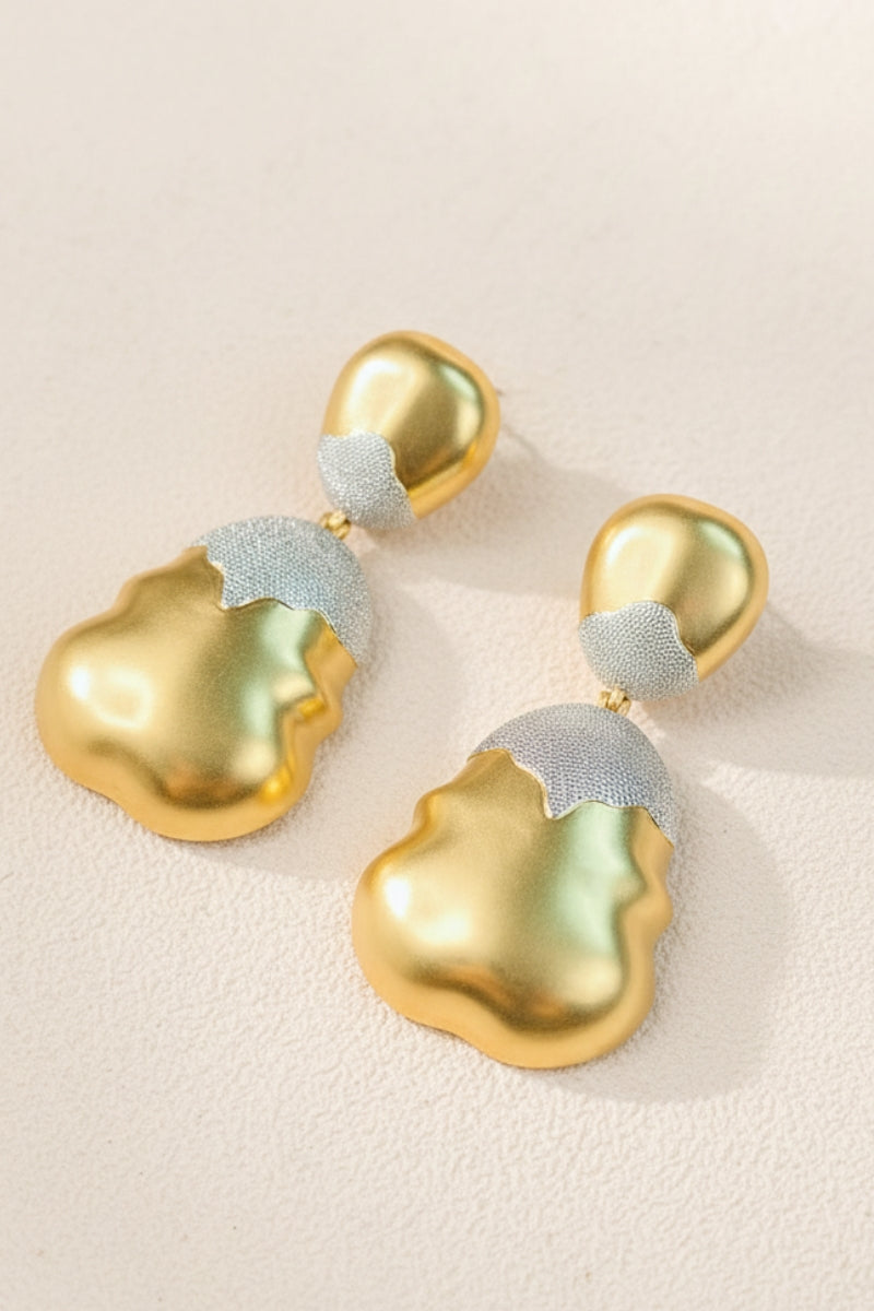 High-detail view of Luna mixed metal earrings with a shimmering frosted silver top and wavy molten gold bottom.