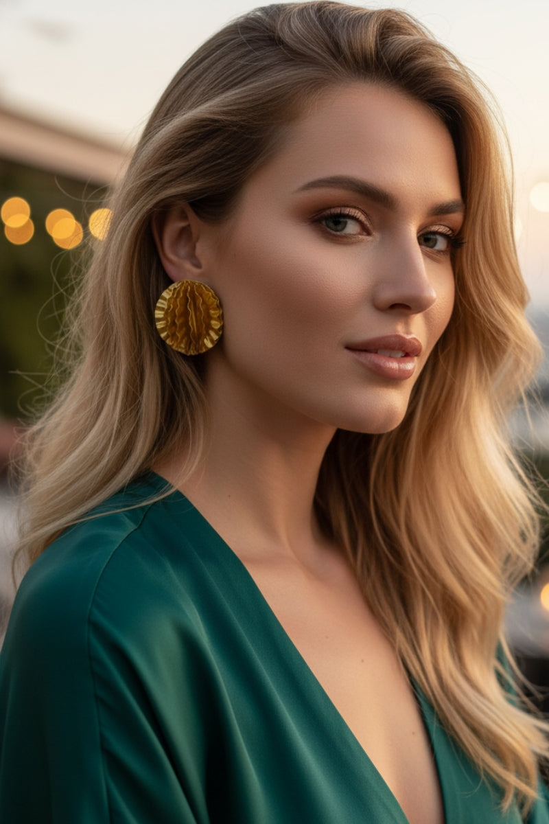 Model wearing Aurelia large gold disc statement earrings with emerald green silk dress, elegant evening gala jewelry for women in New York and London.