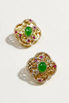 Pair of green crystal quatrefoil stud earrings on a white background