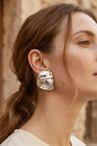 Model wearing liquid silver square statement stud earrings, view 1