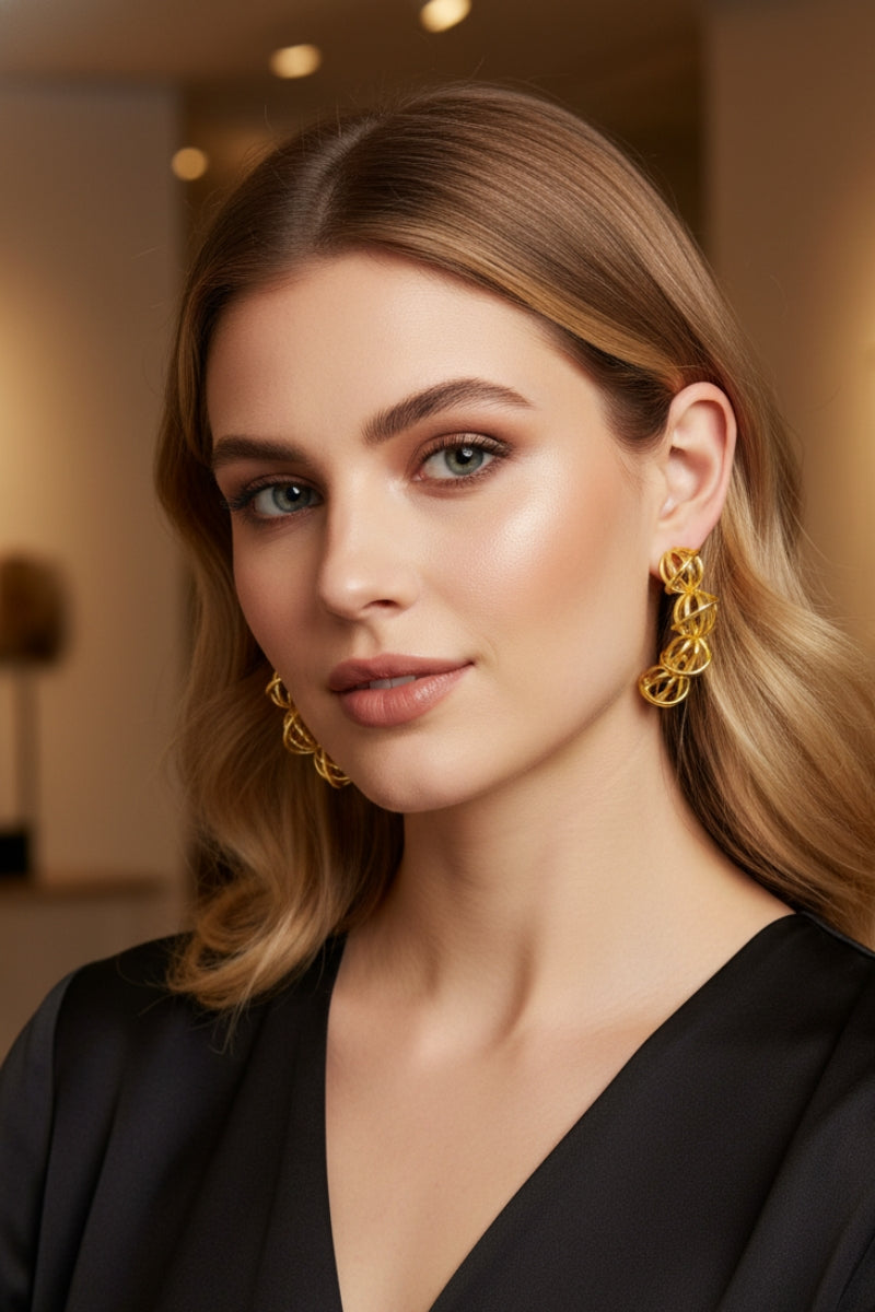 Front view of a elegant woman with a polished look wearing a black V-neck top and a pair of tiered wire-woven orb hoops, demonstrating a versatile option for contemporary capsule wardrobes and sophisticated office accessories.