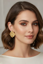 A high-fashion shot featuring the Mirage Earrings, an 18k gold-plated statement piece with an artisanal textured aesthetic.