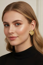A professional lookbook photo of the Mirage Earrings, showcasing the intricate artisanal texture of the gold statement piece.