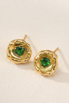 Close up of Molten Emerald Heart stud earrings with irregular 18K gold-plated lava texture surrounding a heart-cut emerald green gemstone, serving as quiet luxury style inspiration for capsule wardrobe daily wear.