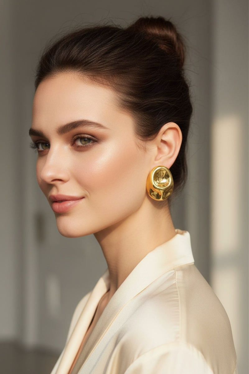 Elegant model wearing large irregular liquid gold earrings, highlighting high-shine reflective finish and mob wife aesthetic.