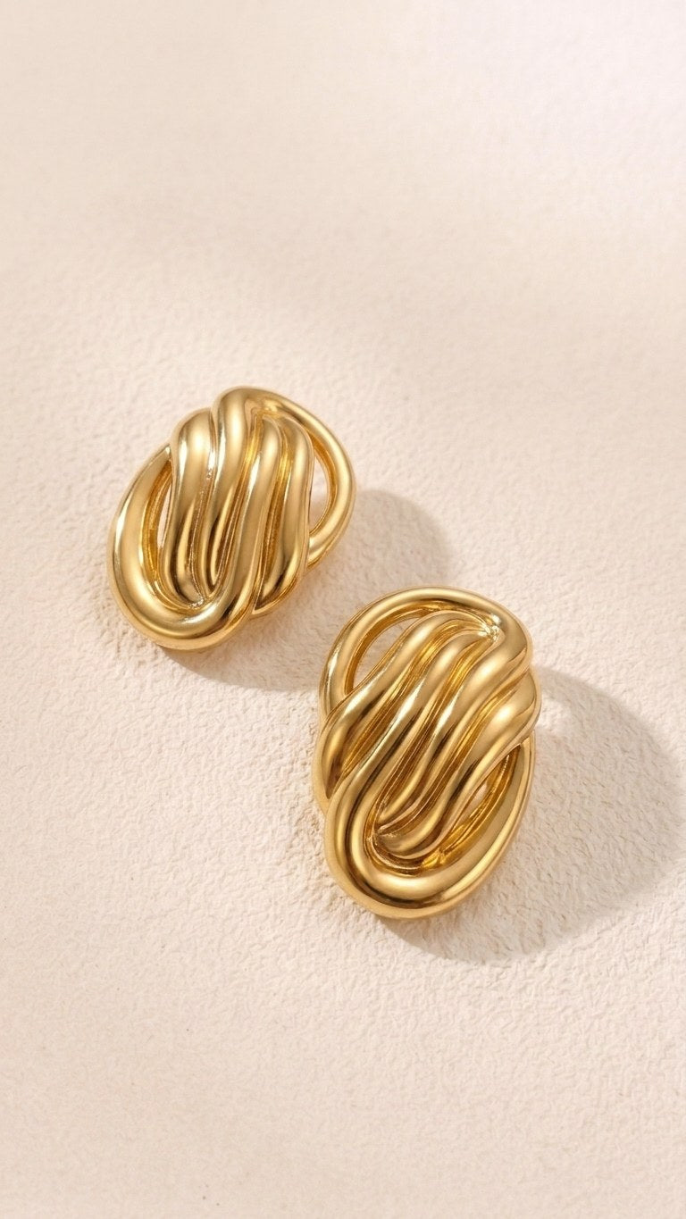 Pair of sculptural oval knot statement stud earrings on a white background
