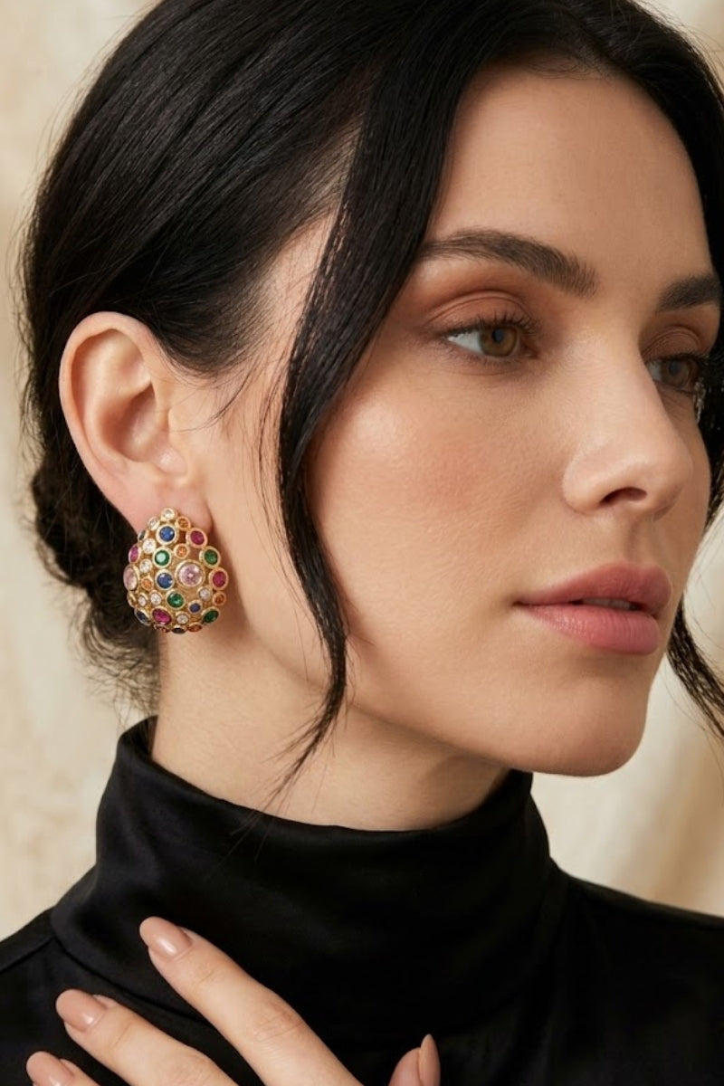 Professional portrait of a woman showcasing Starlight Oval Earrings featuring an intricate cluster of multi-colored stones set in 18K gold plated brass.