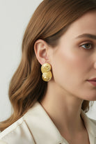 Close-up of a model wearing the Seraphina small gold S-wave stud earring, highlighting its flowing liquid-metal texture.