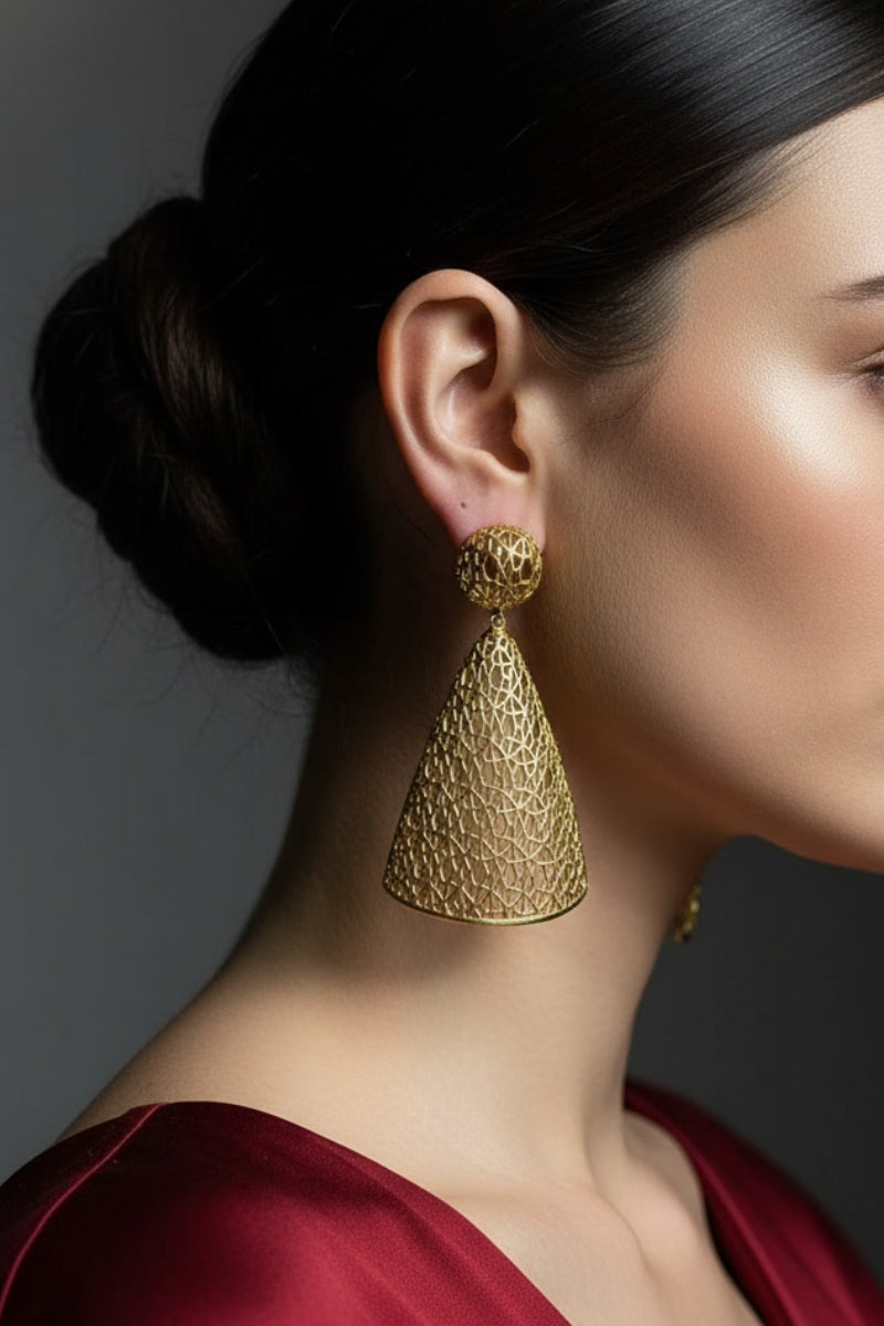 Close-up of Meridian Lattice Drops in 18K gold paired with a burgundy satin dress, showcasing architectural jewelry design.