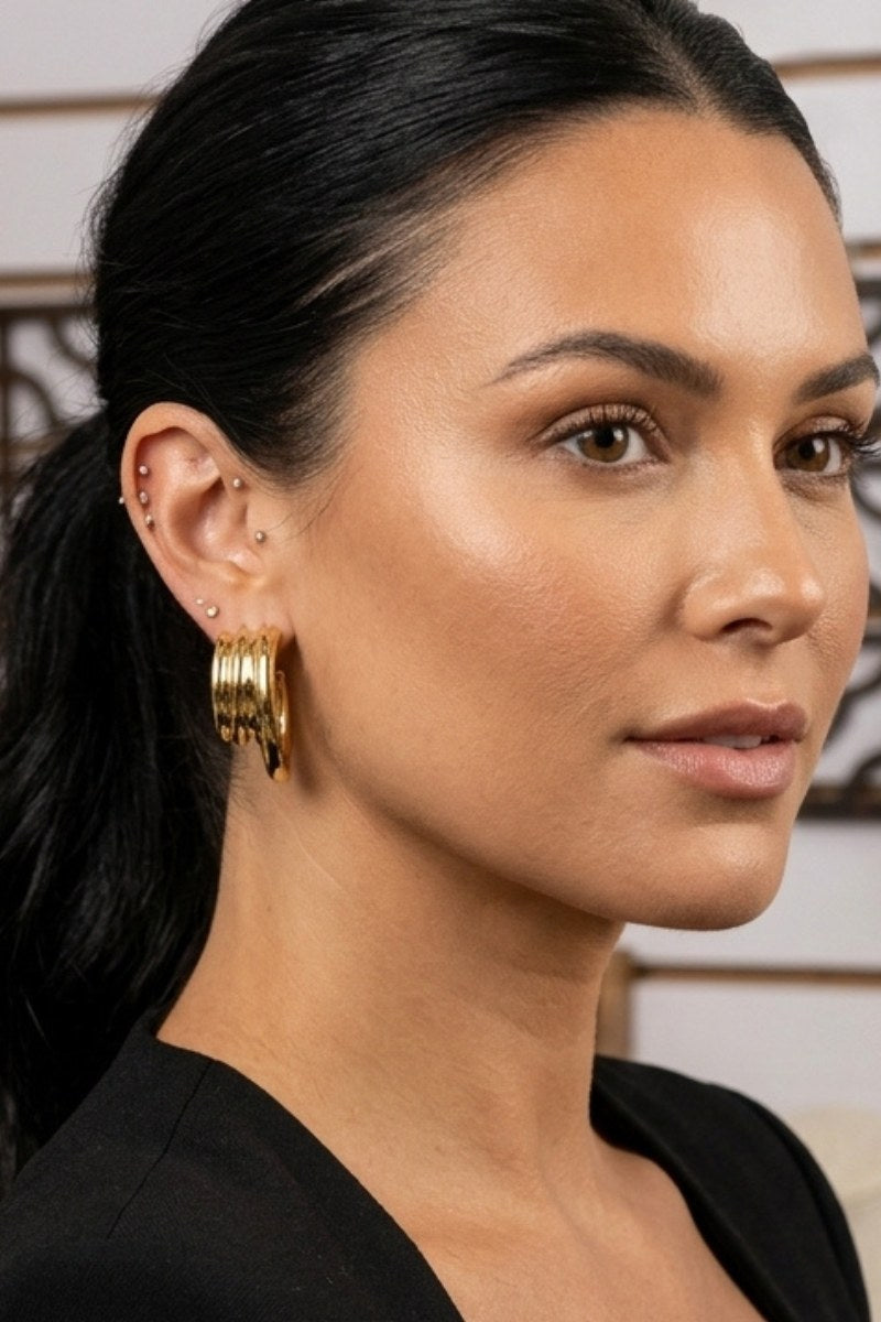 Model wearing triple-ribbed wave hoop earrings, view 2