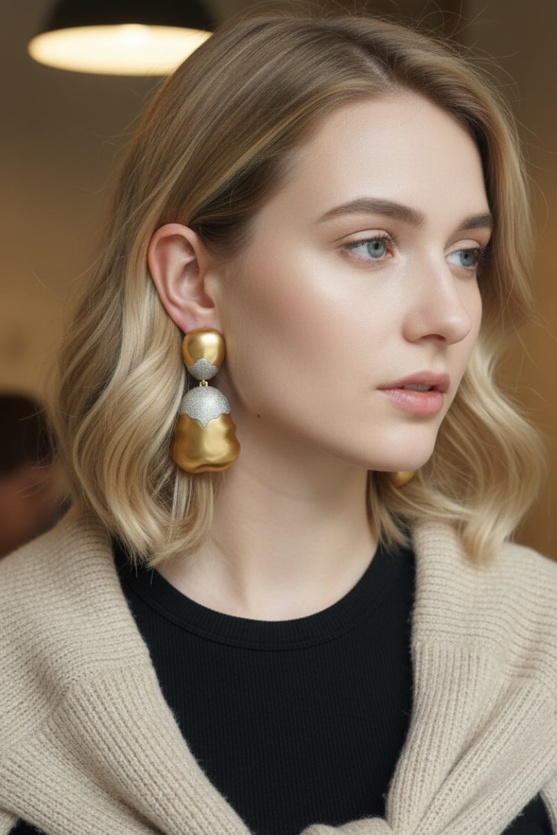 Close-up of model wearing organic shaped mixed metal earrings with casual chic knitwear, highlighting the gold and silver contrast.