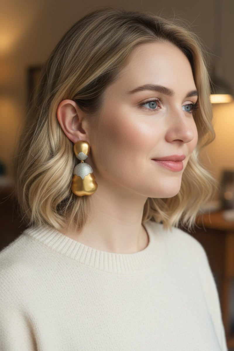Close-up of model wearing organic shaped mixed metal earrings with casual chic knitwear, highlighting the gold and silver contrast.
