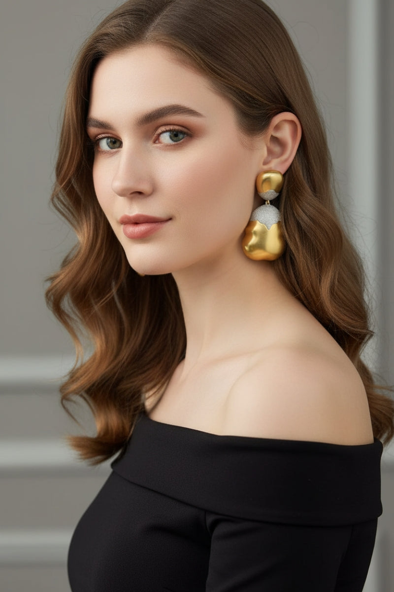 Elegant updo hairstyle showcasing oversized gold and silver mixed metal drop earrings, perfect for wedding guests or black-tie events.