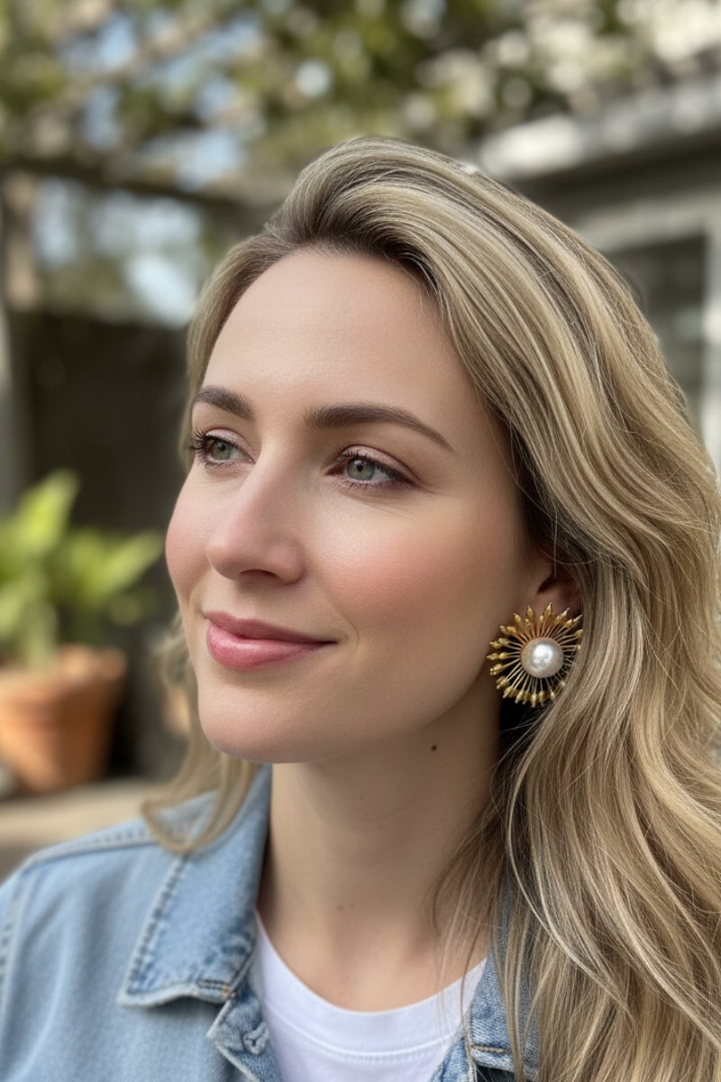 Woman wearing Hera 18K gold sunburst pearl earrings with denim jacket, casual chic daily jewelry style for women in North America.