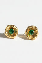 Vintage-inspired organic metal stud earrings featuring vibrant heart-shaped green crystal stones in molten gold frames, displaying nickel-free hypoallergenic sterling silver posts for sensitive ears.