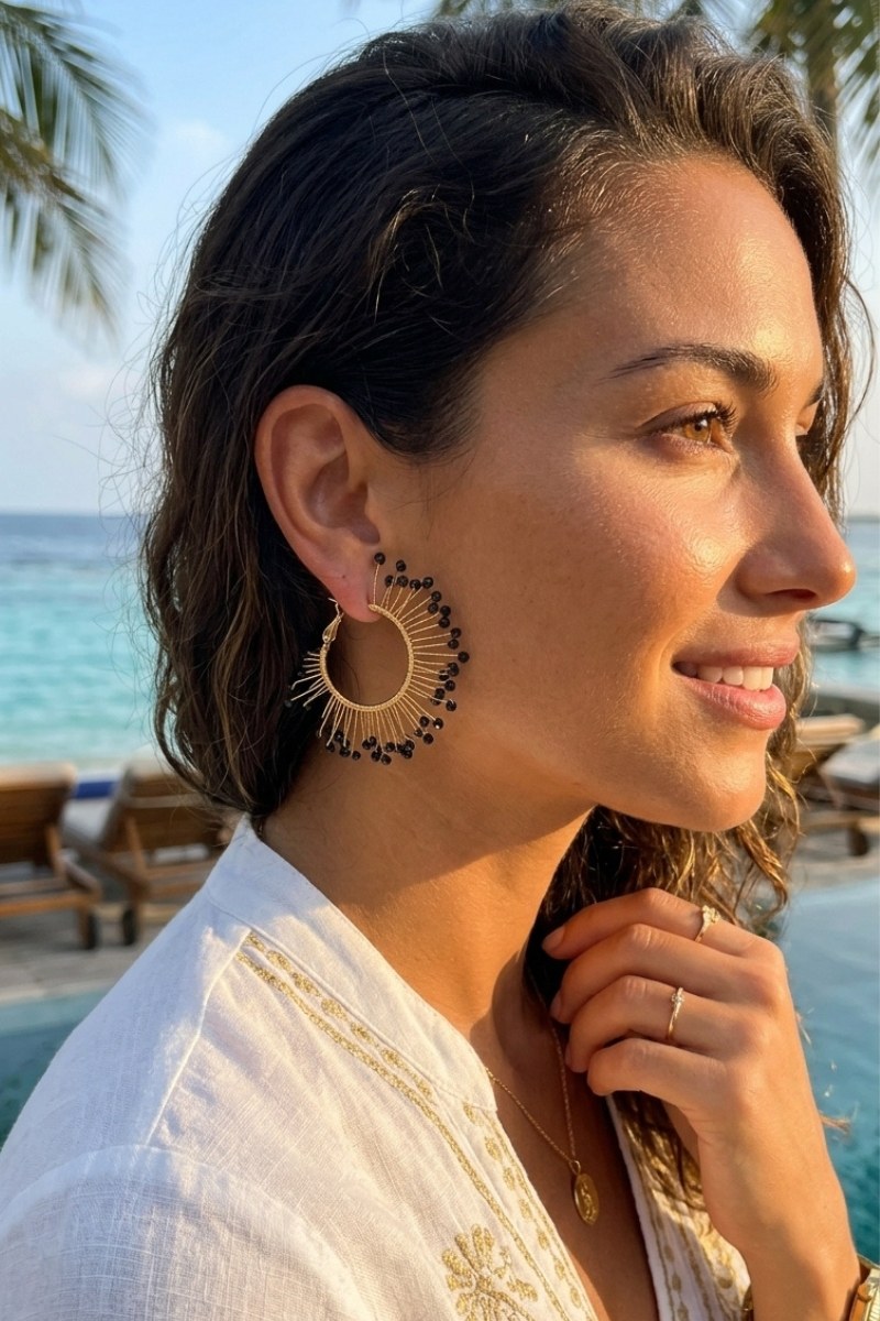 Model wearing solburst wire-wrapped beaded sunburst hoop earrings in the Noir variant, view 2