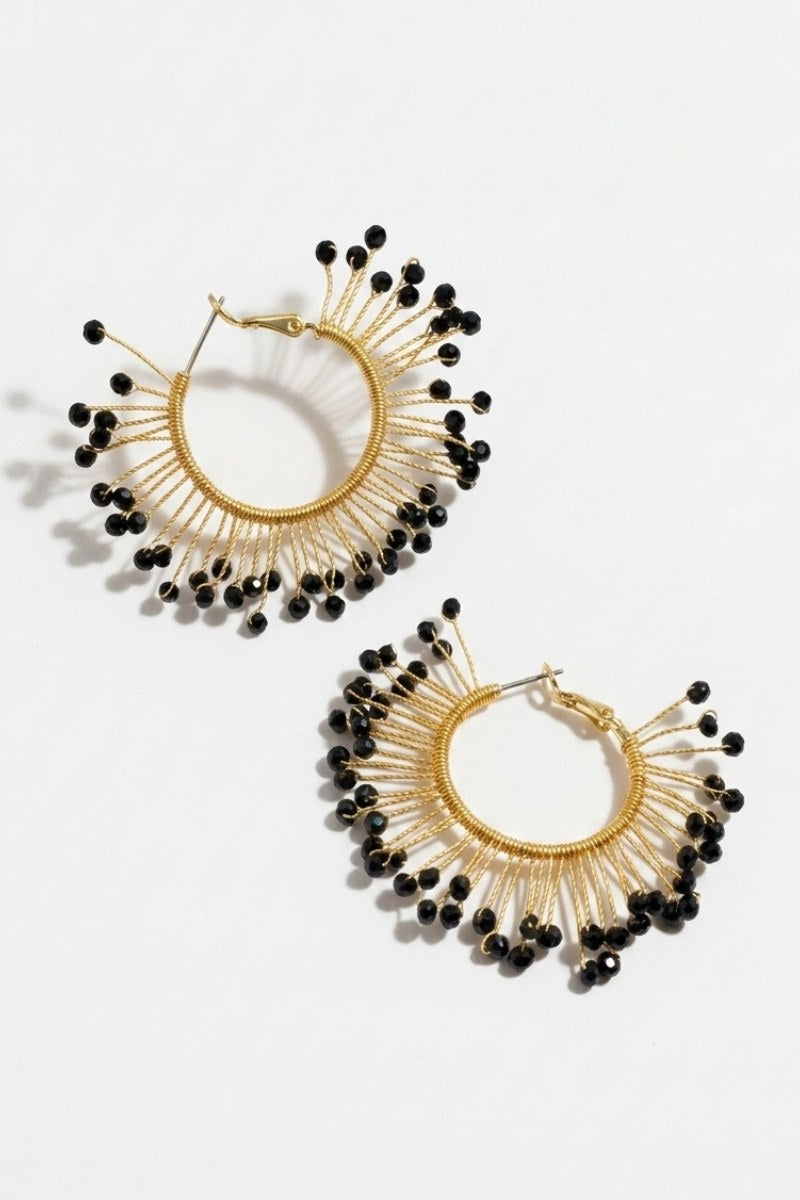 Pair of solburst wire-wrapped beaded sunburst hoop earrings in the Noir variant on a white background