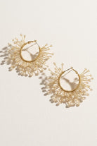 Solburst wire-wrapped beaded sunburst hoop earrings in the Pearl variant on a warm beige background