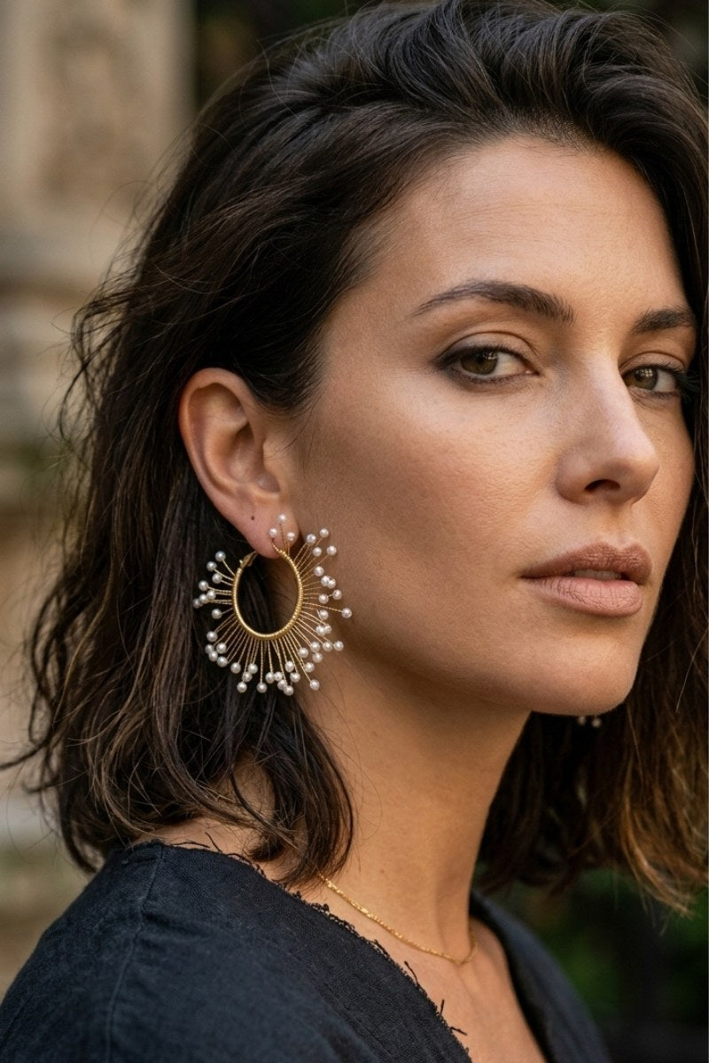 Model wearing solburst wire-wrapped beaded sunburst hoop earrings in the Pearl variant, view 2