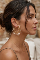 Model wearing solburst wire-wrapped beaded sunburst hoop earrings in the Pearl variant, view 3