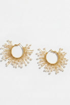 Pair of solburst wire-wrapped beaded sunburst hoop earrings in the Pearl variant on a white background